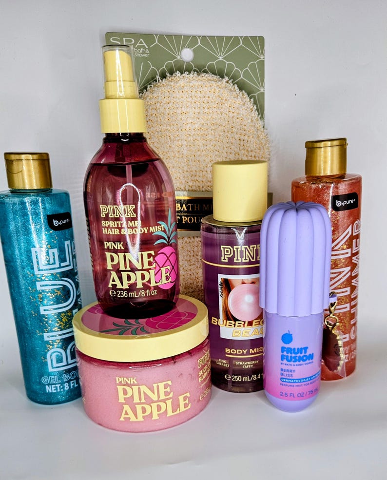 May include: A collection of bath and body products including a blue glitter gel body wash, a Pink Pineapple hair and body mist, a Pink Pineapple body scrub, a Bubble Beach body mist, a purple Fruit Fusion perfume mist, and a shimmer body wash.