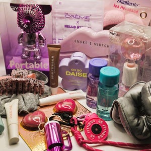 May include: A collection of beauty and lifestyle items including a Bytech portable fan, The Cr&egrave;me Shop Hello Kitty sheet mask, Skintimate spa headband, Vivitar facial globe, Oh So Daise fragrance, lip butter balm, hair claw, and a pink fitness weight keychain.