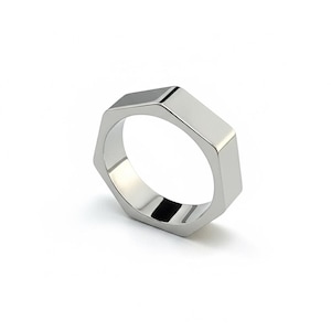 Puede incluir: Un anillo plateado con un diseño hexagonal. El anillo tiene una superficie pulida y reflectante, y la forma es angular y moderna. Es una pieza de joyería.