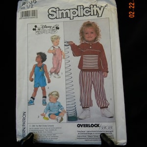 Puede incluir: Un patrón de costura Simplicity para ropa de niños con una camisa y pantalones a rayas rojas y blancas, una camisa y pantalones cortos a rayas azules y blancas, y un mono azul. El patrón incluye instrucciones para usar una máquina de coser overlock o remalladora. El patrón está licenciado por Disney.