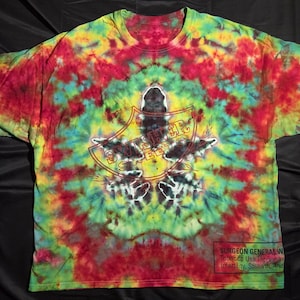 May include: A tie-dye t-shirt in a swirl of red, yellow, green, and blue. The shirt features a graphic with the words "Swisher Sweets" and a shield design. The Surgeon General's warning is printed at the bottom.