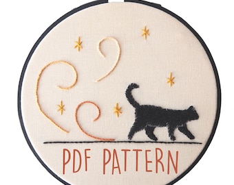 Puede incluir: Un patrón de bordado de silueta de gato negro con líneas en espiral y estrellas sobre un fondo beige. El patrón está en un aro de bordado redondo y dice "PDF PATTERN" en la parte inferior.