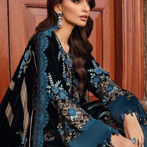 May include: Black velvet ensemble with teal floral embroidery and trim. The outfit features long sleeves with teal cuffs and intricate detailing. The design includes a shawl with striped accents.