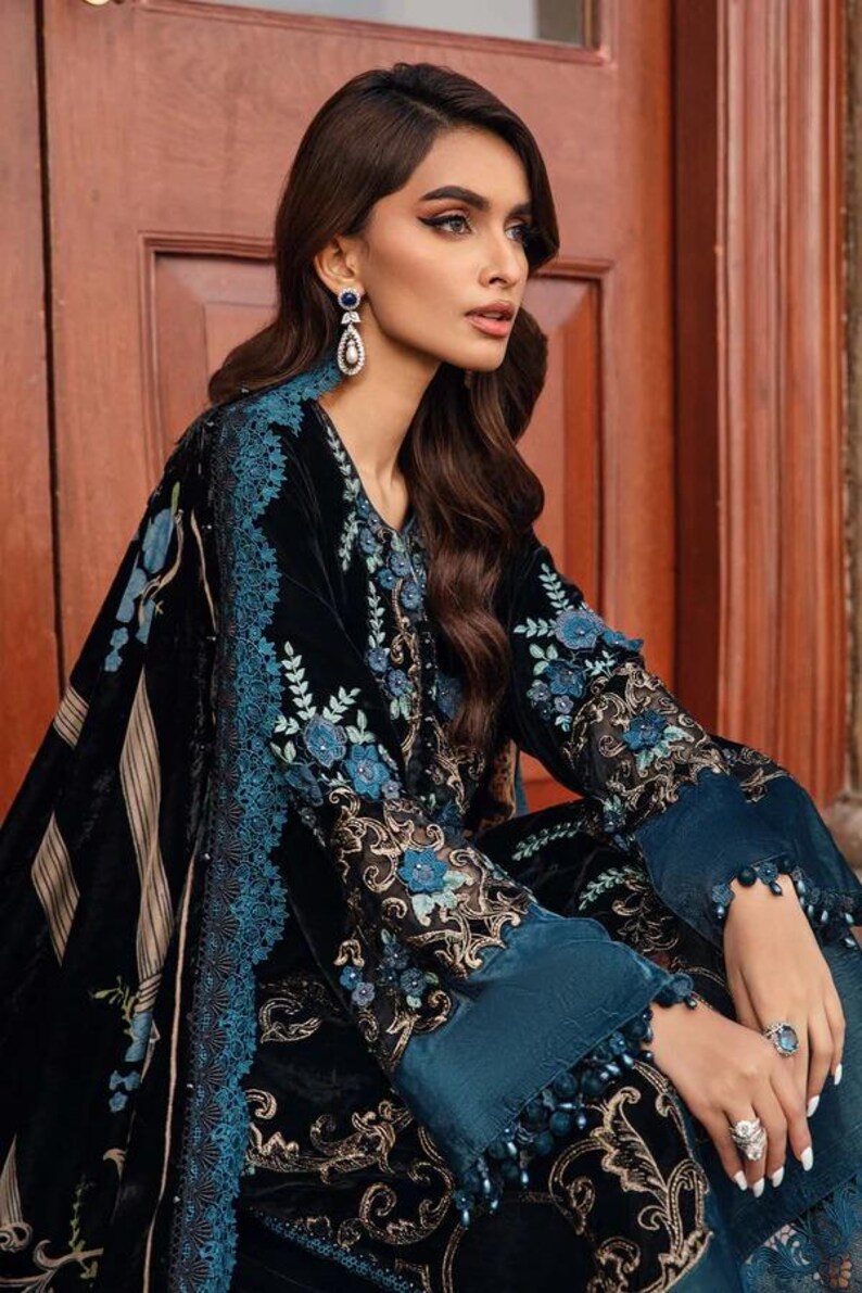 May include: Black velvet ensemble with teal floral embroidery and trim. The outfit features long sleeves with teal cuffs and intricate detailing. The design includes a shawl with striped accents.