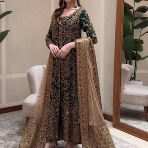 Könnte beinhalten: Ein elegantes, dunkelgrünes und goldfarbenes, besticktes Abendkleid mit passendem, durchsichtigem Schal. Das Kleid hat aufwendige goldene Verzierungen und wird mit transparenten Sandalen mit Absatz kombiniert. Das Outfit ist für besondere Anlässe geeignet.