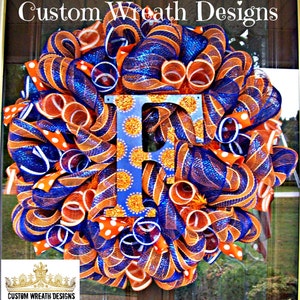 May include: A blue and orange wreath with a large letter "F" in the center. The letter is decorated with gold glitter and white polka dots. The wreath is made of mesh ribbon and is decorated with white polka dot ribbon.