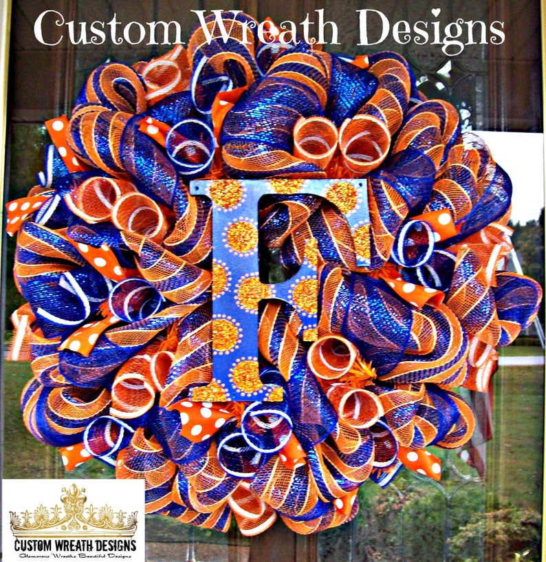 May include: A blue and orange wreath with a large letter "F" in the center. The letter is decorated with gold glitter and white polka dots. The wreath is made of mesh ribbon and is decorated with white polka dot ribbon.