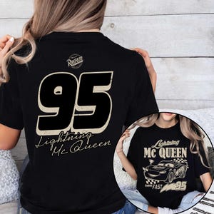 K&ouml;nnte beinhalten: Schwarzes T-Shirt mit der Nummer 95 in verblichener Schrift und dem Schriftzug "Lightning McQueen" darunter. Das Shirt hat auch eine kleine Grafik eines Rennwagens mit dem Text "Think Fast".