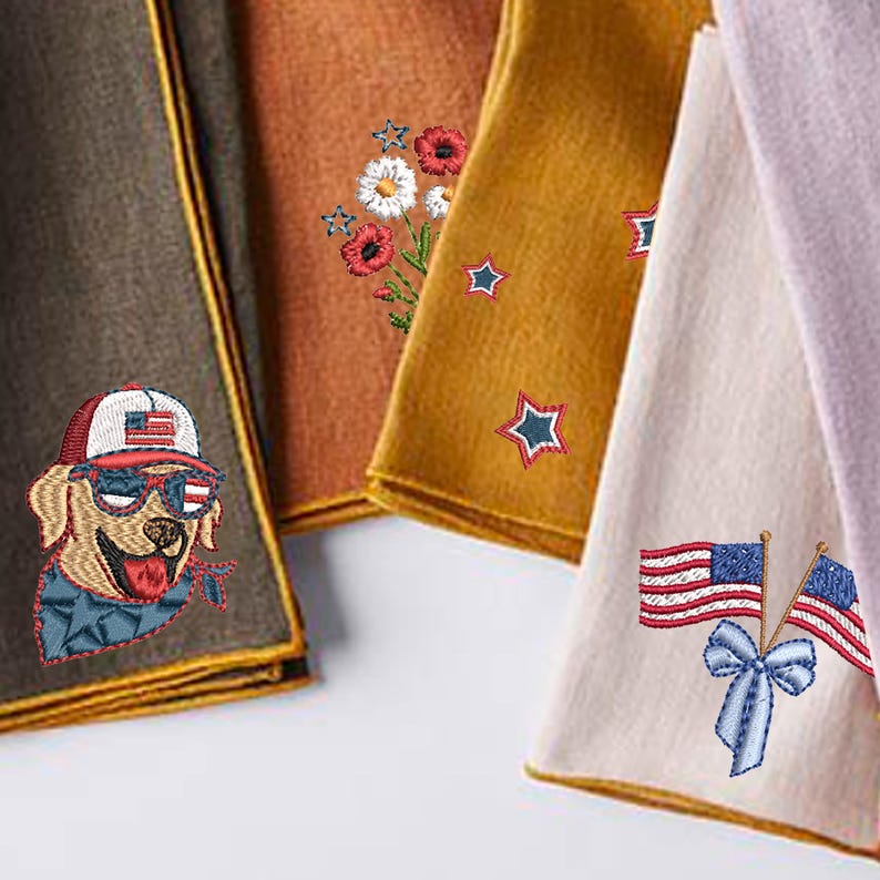 Puede incluir: Primer plano de varias toallas decorativas dobladas. Una toalla presenta un perro bordado con gafas de sol y un sombrero con la bandera estadounidense. Otras toallas tienen flores, estrellas y banderas americanas bordadas.