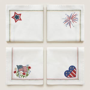 Puede incluir: Cuatro servilletas cuadradas blancas con dise&ntilde;os patri&oacute;ticos bordados. Cada servilleta presenta un dise&ntilde;o diferente: una estrella, fuegos artificiales, una bandera americana con flores y un coraz&oacute;n. Los bordes est&aacute;n ribeteados con costuras de colores.