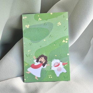 May include: A rectangular card with a green background featuring an illustration of a figure in a white robe with a red sash and a white sheep. The illustration is set in a grassy field with yellow flower accents.