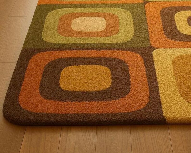 This rug features a retro geometric design with bold, rounded square patterns in warm shades of orange, mustard yellow, olive green, and brown. Its soft texture and mid-century modern style make it a standout piece for any living room or bedroom. The combination of earthy tones and clean, vintage-inspired shapes gives the rug a cozy yet stylish appeal — perfect for adding warmth and personality to your space.