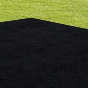 May include: A large, black rectangular rug is placed on a green grassy surface. The rug's dark color contrasts with the bright green grass, creating a simple yet striking visual. The rug appears to be made of a textured material.