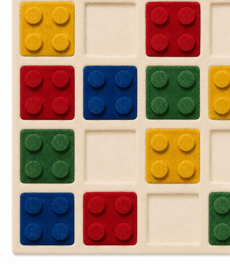 May include: A square rug featuring a grid pattern with raised, textured blocks in primary colors including red, blue, yellow, and green. Each block has four circular studs on its surface, set against a neutral, cream-colored background.