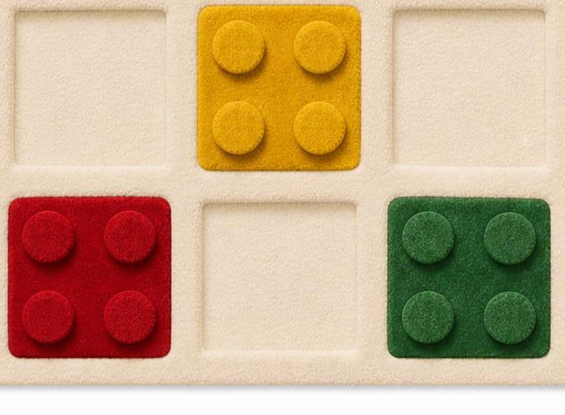 May include: A cream-colored grid board featuring three square, textured game pieces. One yellow piece with four circular studs is in the top center, one red piece with four studs is in the bottom left, and one green piece with four studs is in the bottom right.