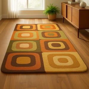 This rug features a retro geometric design with bold, rounded square patterns in warm shades of orange, mustard yellow, olive green, and brown. Its soft texture and mid-century modern style make it a standout piece for any living room or bedroom. The combination of earthy tones and clean, vintage-inspired shapes gives the rug a cozy yet stylish appeal — perfect for adding warmth and personality to your space.