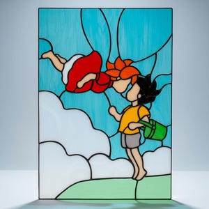 May include: Stained glass panel featuring a whimsical scene of two figures. One figure is in a red dress, the other in a yellow shirt, holding a green bucket. The background is a light blue sky with white clouds and green grass.