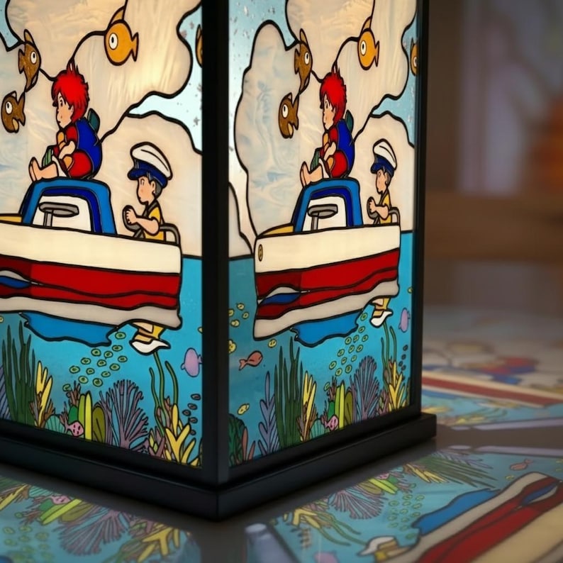 May include: A stained glass lamp with a black frame. The lamp features a nautical scene with a red, white, and blue boat, cartoon figures, fish, and underwater plants. The lamp is sitting on a patterned surface.