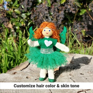 May include: A handmade fairy doll with green wings, a green tulle skirt, a white heart on her chest, and red yarn hair.  Customize hair color and skin tone.