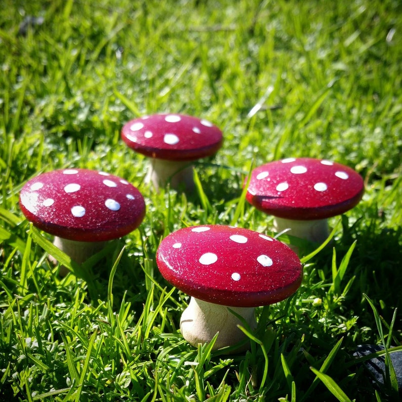 May include: Four red and white polka dot mushroom shaped ornaments. The mushrooms are made of wood and have a glossy finish.