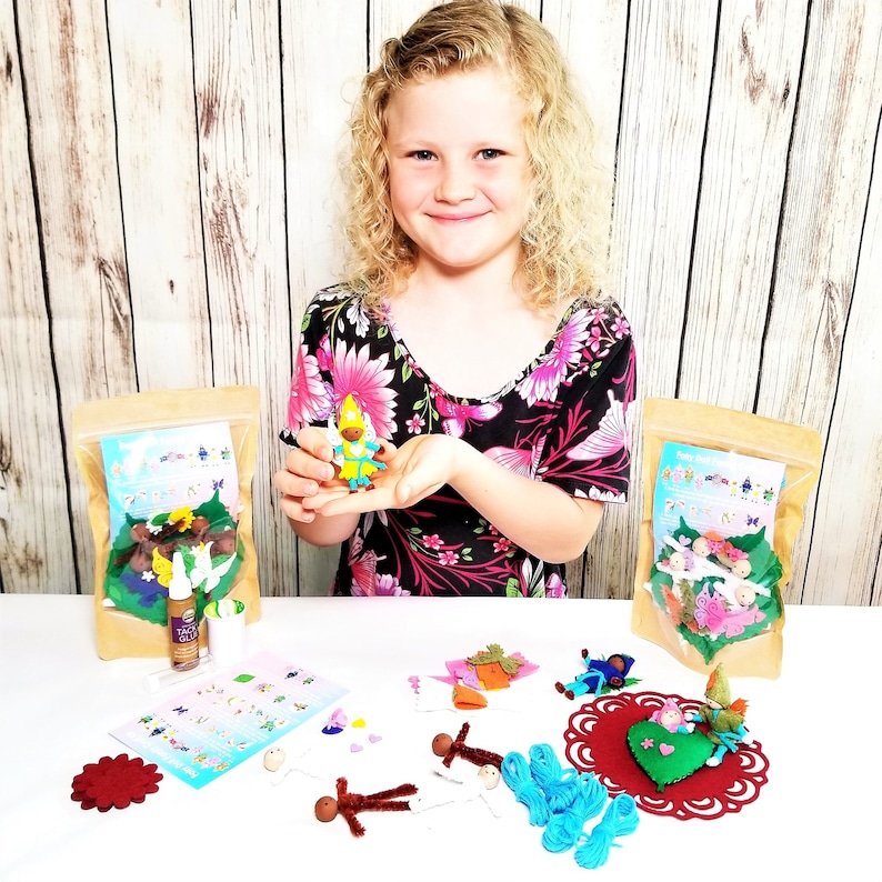 May include: A craft kit for making felt fairy dolls. The kit includes felt pieces, pipe cleaners, beads, and glue. A young person is holding a completed fairy doll.