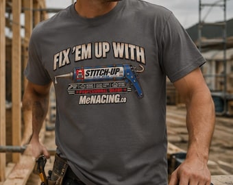 May include: A charcoal grey short-sleeve t-shirt featuring a graphic of a blue caulking gun with the text "FIX 'EM UP WITH STITCH-UP" and "MeNACING.co" printed on the front. The design includes small icons and additional text details.