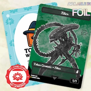 May include: A rectangular game card featuring a black alien creature illustration on a green background with the text Alien, Token Creature - Alien, and 1/1. A second light blue card with a logo and a red 100% hand-drawn 100% homemade seal are visible.