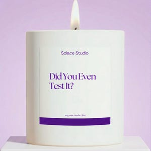 May include: A lit white soy wax candle with the text "Did You Even Test It?" in purple. The candle is from Solace Studio and is 9oz. The background is a soft purple.