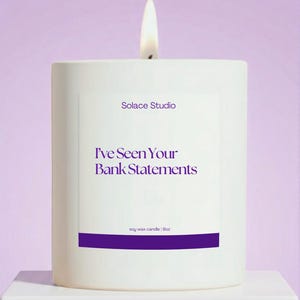 May include: A white soy wax candle with a lit wick. The candle has the text "Solace Studio" and "I've Seen Your Bank Statements" in purple. The candle is 9oz.