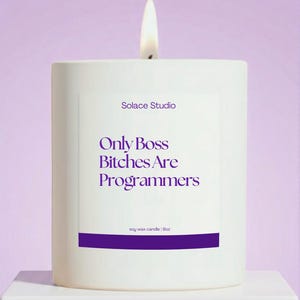 May include: A white soy wax candle with a lit wick, featuring the text "Only Boss Bitches Are Programmers" in purple. The candle is from Solace Studio and is 9oz.