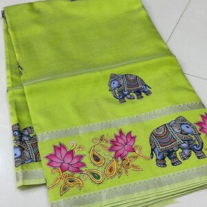 May include: A lime green textile with a decorative border featuring elephants, lotus flowers, and paisley designs. The elephants are blue with detailed patterns. The border has a silver trim.