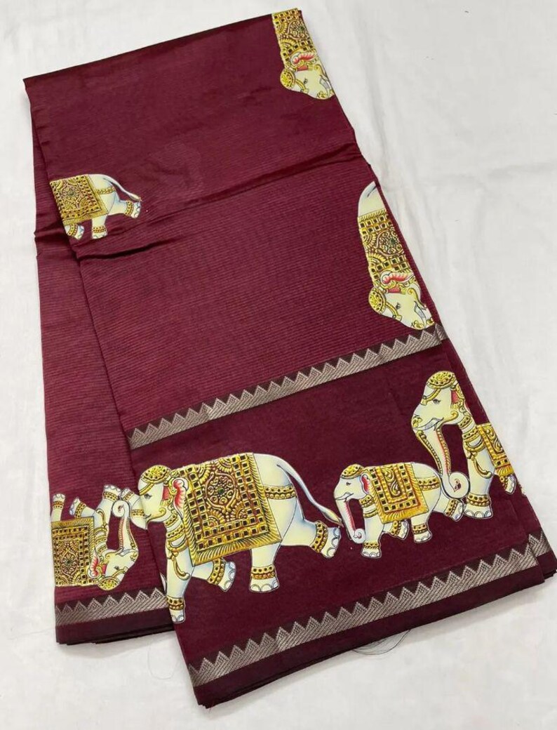 May include: A maroon textile with a repeating pattern of white elephants adorned with gold and yellow decorative elements. The fabric has a subtle striped texture and a decorative border.
