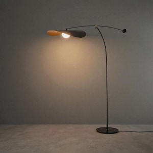 May include: A modern black floor lamp with a curved arm and a unique, petal-shaped lampshade. The lampshade is a combination of black and light brown, with a bright light emanating from the center. The lamp has a round base and a minimalist design.