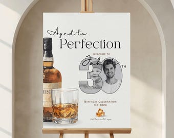 May include: A rectangular birthday sign featuring the text Aged to Perfection, Welcome to Jake's 30th Birthday Celebration, and 3.7.2026. The design includes a whiskey bottle, a glass with ice, a photo of a child and an adult inside the number 30.