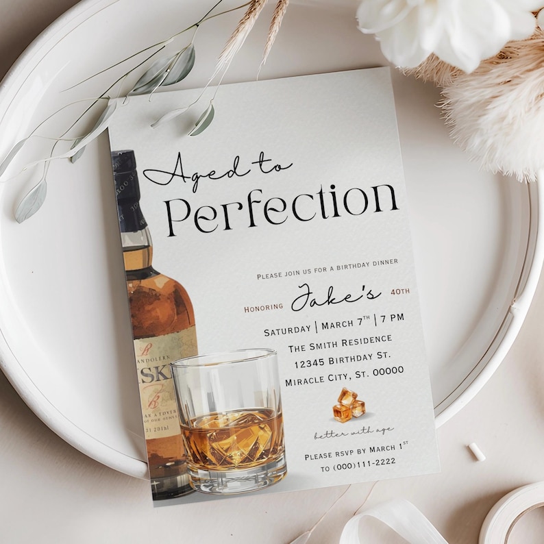 Peut inclure: Invitation d'anniversaire "Aged to Perfection" avec une bouteille de whisky et un verre de whisky avec des gla&ccedil;ons. L'invitation comprend le texte "Jake's 40th" et les d&eacute;tails de l'&eacute;v&eacute;nement. Le design est sur fond blanc.