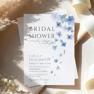 May include: A white invitation for a bridal shower with blue floral accents. The text reads "BRIDAL SHOWER" and includes event details such as the date, time, and location. The invitation is decorated with watercolor-style blue flowers.