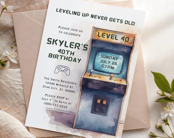 May include: A rectangular birthday invitation card featuring a watercolor-style arcade cabinet illustration. Text reads: LEVELING UP NEVER GETS OLD, PLEASE JOIN US TO CELEBRATE SKYLER'S 40TH BIRTHDAY, SUNDAY JULY 26 @7PM, THE SMITH RESIDENCE, AND RSVP DETAILS.