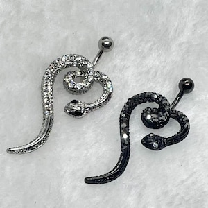May include: Two belly button rings in the shape of a snake. One is silver-toned with clear crystals, the other is black with black crystals. Both have a curved snake body and a ball at the top.