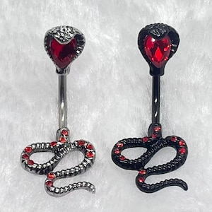 May include: Two belly button rings with snake designs. One is silver-toned with red gems and a red gem in the snake's head. The other is black with red gems and a red gem in the snake's head.