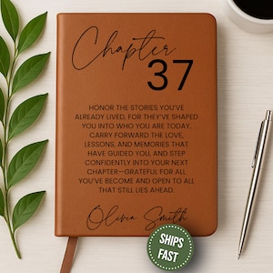 May include: A brown leather journal with the words "Chapter 37" and inspirational text. The journal includes a ribbon bookmark and the name "Olivia Smith". A silver pen and a cup of coffee are also visible.