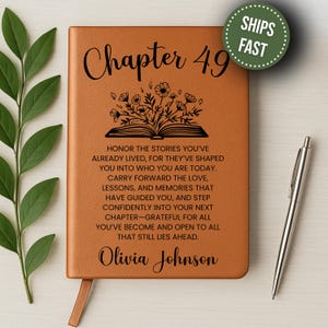 May include: A brown leather journal with the words "Chapter 49" and a floral design. The journal includes inspirational text and the name "Olivia Johnson". A silver pen rests beside the journal. A green circle with the words "SHIPS FAST" is in the upper right corner.