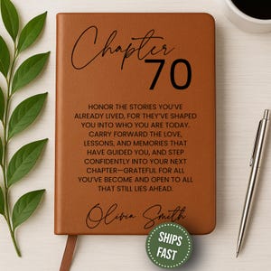 May include: A brown leather journal with the words "Chapter 70" in black script. The journal includes inspirational text and the name "Olivia Smith." A silver pen and a cup of coffee are next to the journal.