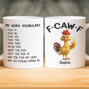 Op de afbeelding: Twee witte keramische mokken. Eén mok heeft een lijst met krachttermen onder de kop "MY WORK VOCABULARY". De andere mok toont een cartoonhaan die de middelvinger opsteekt, met de tekst "F-CAW-F" en de naam "Sophia".