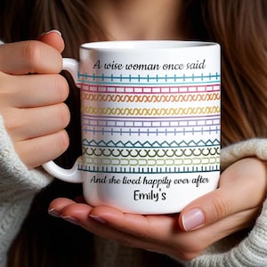 May include: White ceramic mug with a handle, featuring colorful geometric patterns and the text "A wise woman once said... And she lived happily ever after Emily's". The mug is held by a person.