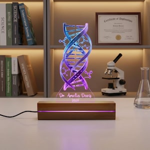 May include: A DNA helix-shaped LED lamp with a wooden base. The lamp glows with blue and purple light. The base has the text "Dr. Amelia Davis 2026". A microscope and books are in the background.