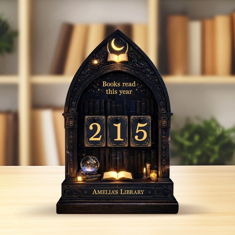 May include: A black wooden bookshelf-shaped display with the text "Books read this year" and the number "215" in gold. The display also features a glowing open book, a crystal ball, and the text "Amelia's Library".