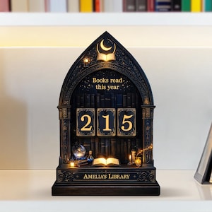 May include: A dark wooden bookshelf-shaped display with the text "Books read this year" and the number "215". The display has a crescent moon and open book design at the top, with the words "Amelia's Library" at the bottom.