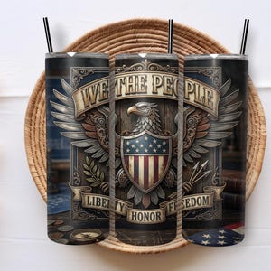 Puede incluir: Un vaso cilíndrico con pajita negra que presenta un diseño patriótico. El gráfico muestra un águila calva con las alas extendidas, un escudo con estrellas y rayas, y pancartas con el texto WE THE PEOPLE, LIBERTY, HONOR, y FREEDOM.