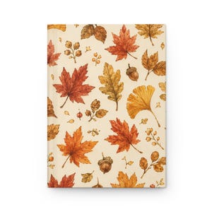 May include: A rectangular notebook featuring a cream-colored cover with a repeating pattern of autumn leaves in shades of orange, red, and brown, interspersed with small brown acorns and delicate sprigs of berries across the entire surface.