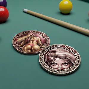 May include: Two round, bronze-colored coins with detailed illustrations and text. One coin features a woman in lingerie with the text "HEADS I GET TAIL". The other coin shows a woman's eyes with the text "TAILS I GET HEAD".